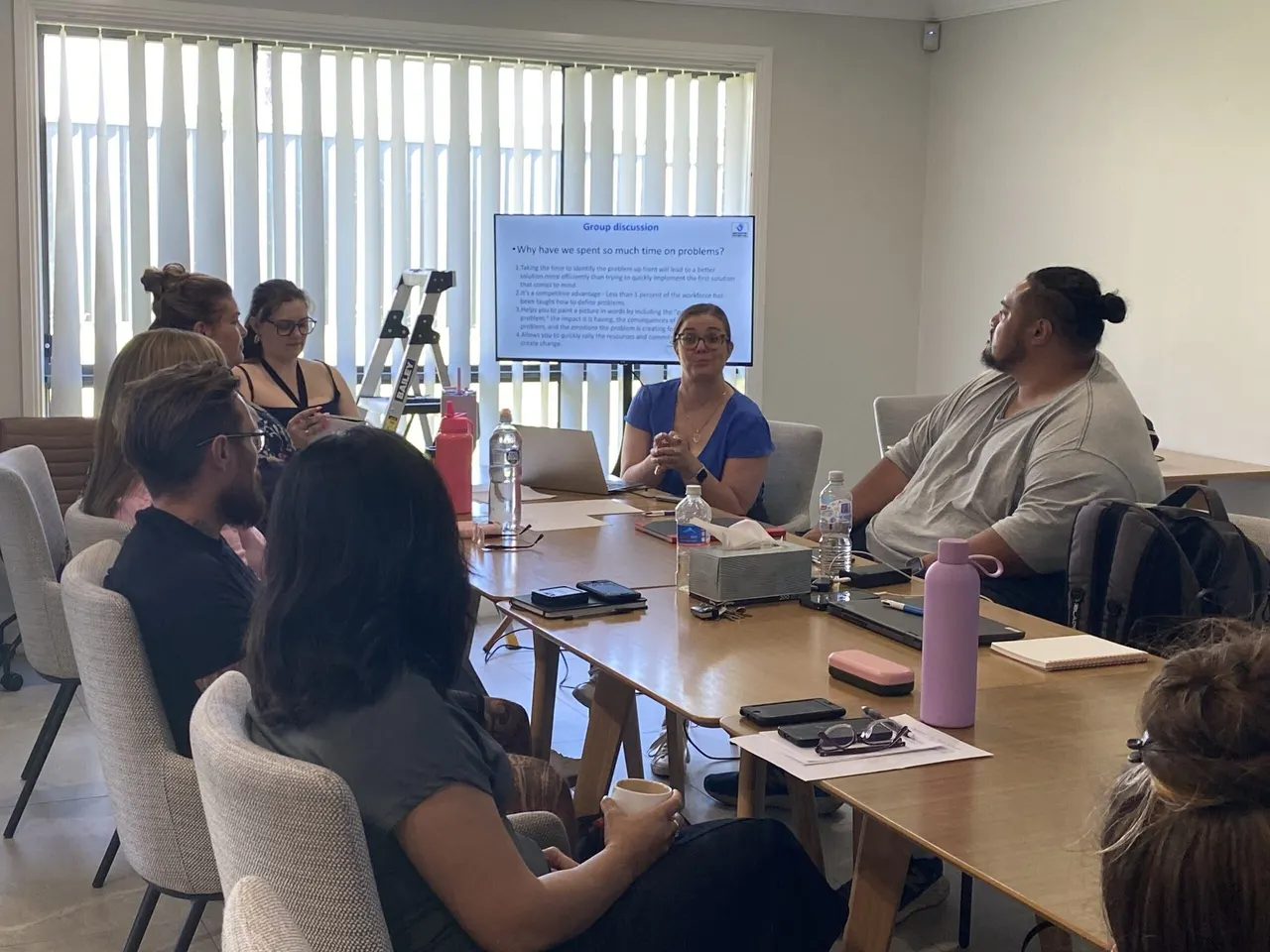 Angela leading a group discussion with a provider team around a boardroom table